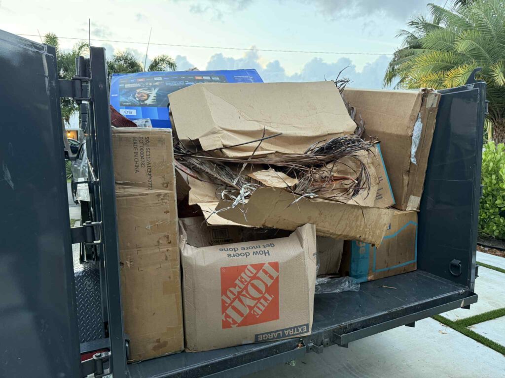 Back of High-Caliber Junk Removal truck filled with cardboard and debris from a cleanout.
