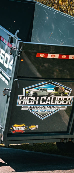 High-Caliber Junk Removal team member standing in front of a branded junk removal trailer.