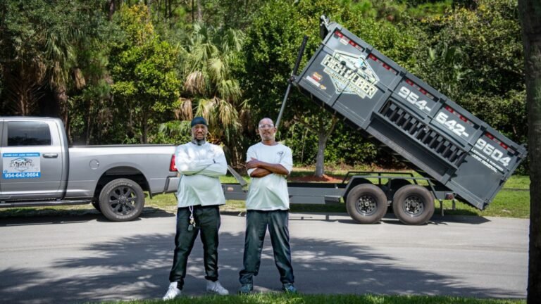 High Caliber Junk Removal crew standing in front of a truck and raised dump trailer