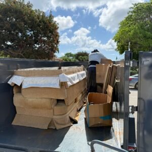Worker loading a couch into High Caliber junk removal trailer