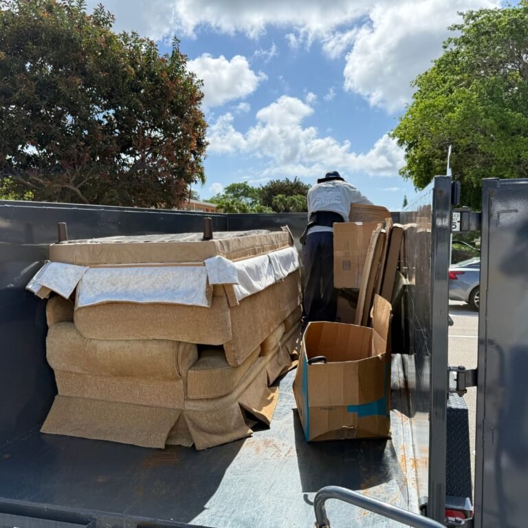High Caliber Junk Removal crew loading furniture and boxes into dump trailer during residential cleanout in Broward County Florida