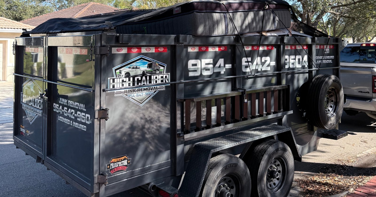 High Caliber Junk Removal charcoal grey 7x14 dump trailer fully loaded for junk removal service in Broward County Florida