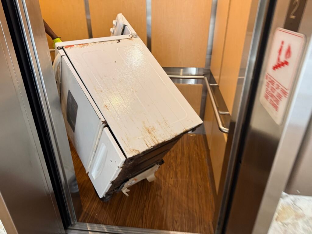 Appliance removal crew hauling a stove in Pompano Beach, FL
